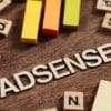 Googleアドセンス合格をテーマにした木製ブロックのイメージ。木の机の上に「ADSENSE」の文字とカラフルな棒が並び、ブログ審査対策を象徴している。