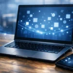 Microsoft 365をお得に購入する方法を象徴するデスク上のノートPC、電卓、スマホのイメージ。青い光が広がるデジタルな雰囲気