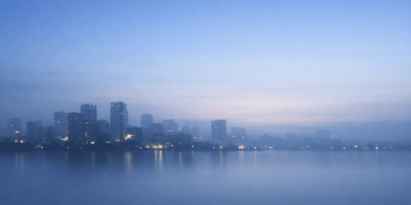 静かな夜明け前の青灰色の都市風景。穏やかな空とぼんやりしたビルのシルエットが広がる、落ち着いた雰囲気のプロフィール背景画像